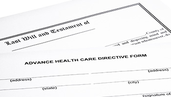 Close-up of a Last Will and Testament form and an Advance Health Care Directive form, partially filled out, symbolizing end-of-life planning and legal documentation