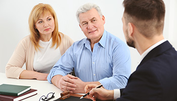 a couple of mature adults talking to another man in a suit, representing Estate Planning